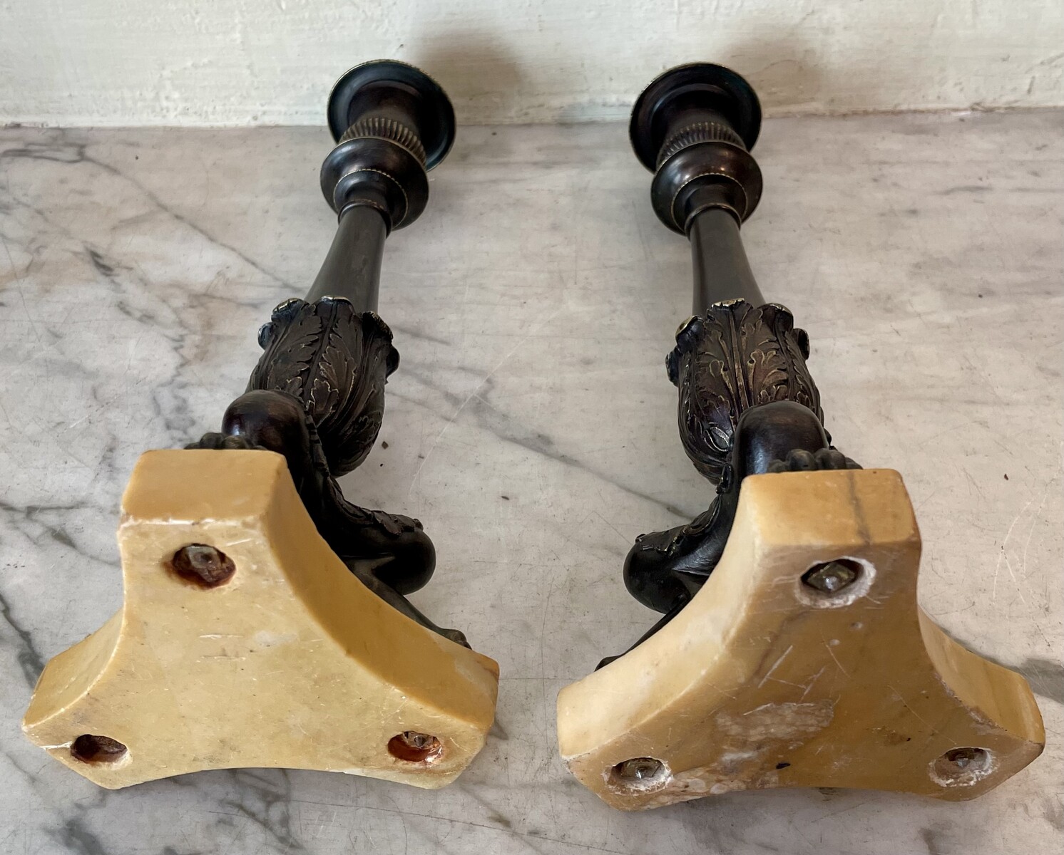 Pair of Restoration style tripod candlesticks on a marble base.
