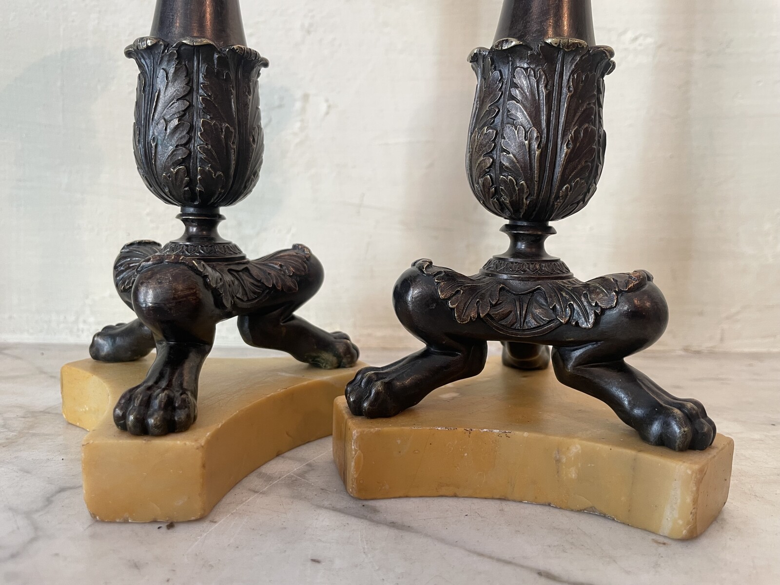 Pair of Restoration style tripod candlesticks on a marble base.