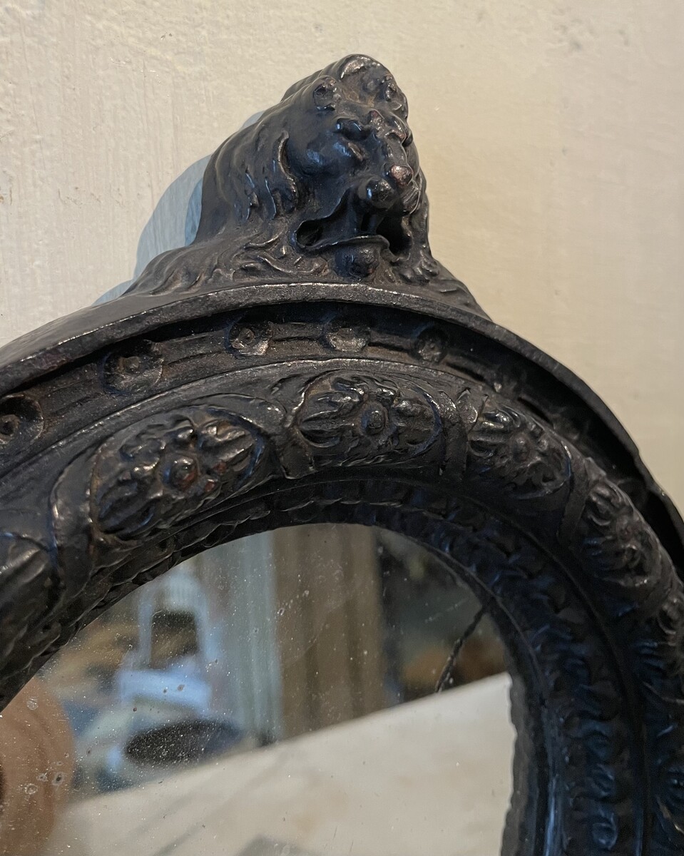 Small round mirror, decorated with flower frieze and lion bust, Regence period